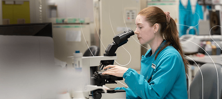 A women reviews specimens in a lab using a microscope at Awanui Labs to represent Brother Labelling Solutions