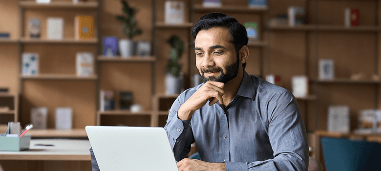 A businessman sitting in a cool office reading the latest news and updates on a laptop